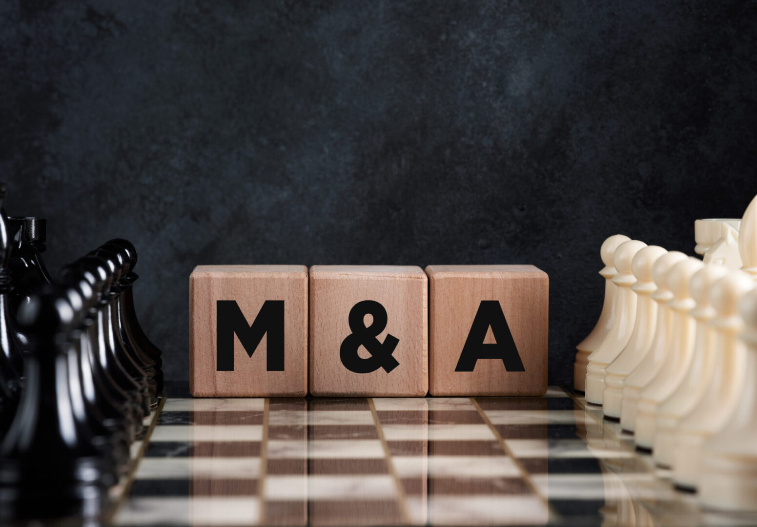 Chessboard with chess pieces and wooden blocks with the word mergers and acquisitions (M&amp;A). Business merger and acquisition strategy concept.